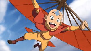 A smiling Ang flies through the sky on his staff-glider in Nickelodeon's Avatar: The Last Airbender