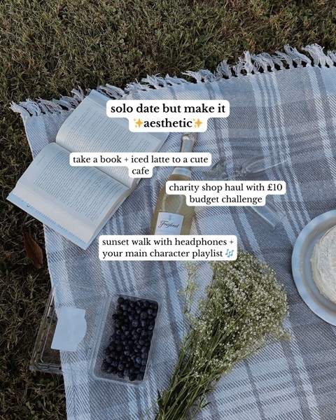 A picnic blanket with a book, some fruit, and flowers, with information about having a solo date.
