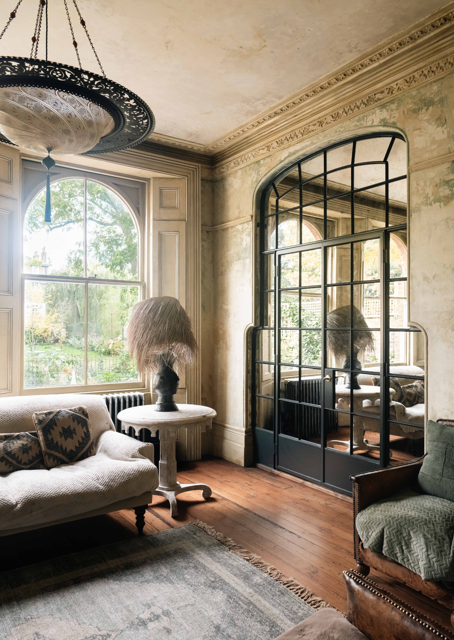 dramatic sitting room with crown molding, wooden floors, crittal doors and a furry lamp