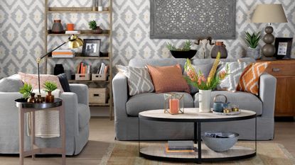 Modern living room with grey geometric wallpaper, grey sofa, assorted coloured geometric cushions. 