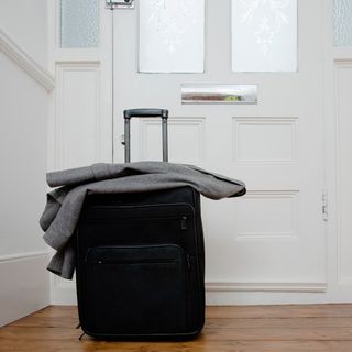white door with black suitcase and wooden floor