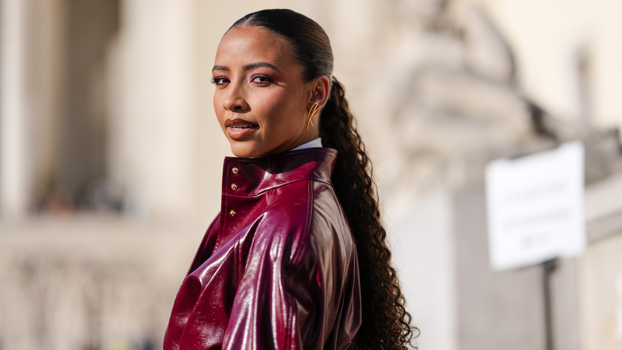 best conditioners - Flora Coquerel wears gold earrings, white buttoned up long sleeve shirt, burgundy bordeaux necktie, shiny burgundy bordeaux belted leather jacket - getty images 2204169564