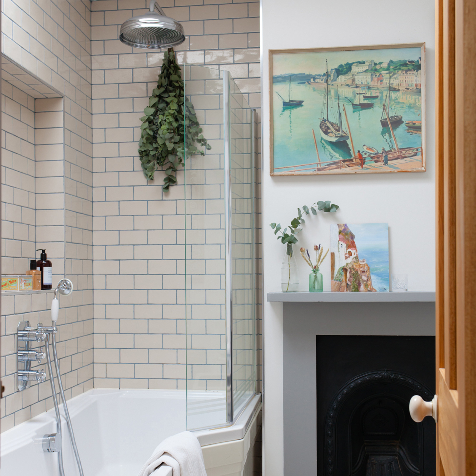 bathroom with a white bath and silver shower head and cream metro tiles with blue grout