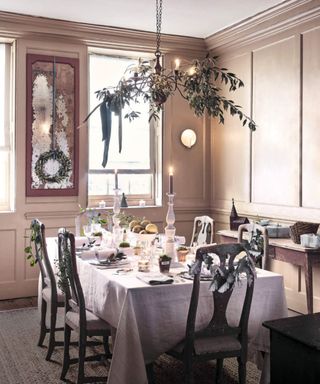 Dining room with wood panelled walls and table laid for a meal with foliage decorations on the chairs.