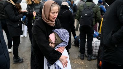 A woman hugs a girl as refugees from Ukraine wait for a transport at the Moldova-Ukrainian border's checkpoint near the town of Palanca on March 1, 2022. 