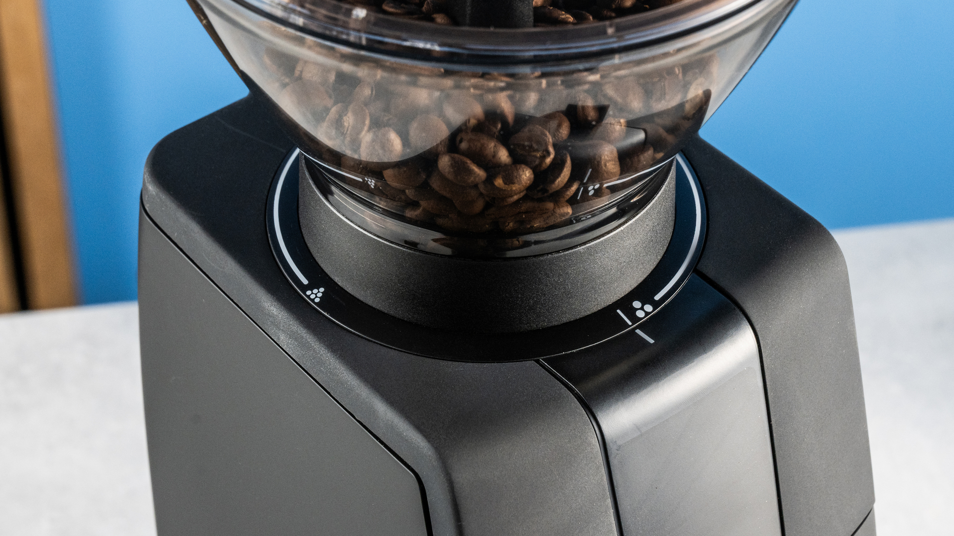 the baratza encore esp pro coffee grinder photographed against a blue tom's guide background with a bag of coffee to the side and showing the grinder in action