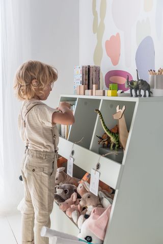 Playroom storage in open shelves with cuddly toys and child