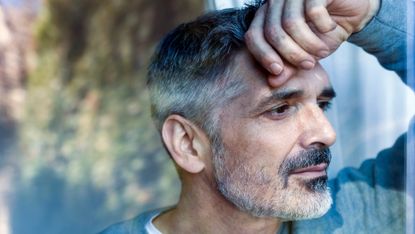 Mature man looking pensively out of window