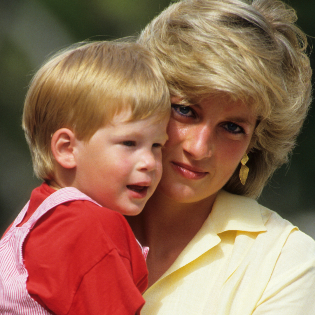 Princess Diana has bouffant blonde hair and cradles Prince Harry, who has bright red hair.