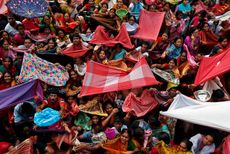 Hindu devotees hold up scarves to receive rice offerings being distributed by the temple authority on the Annakut festival in Kolkata, India.
