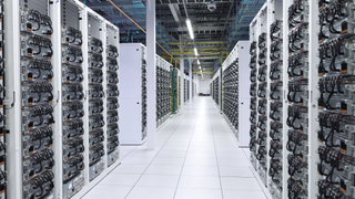 Image of xAI&#039;s Colossus AI supercluster. Two rows of server racks continue into the distance.