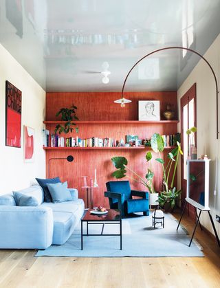 small living room with red walls and light blue chair and rug