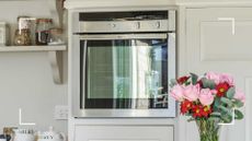 pale grey kitchen with built in oven at eye level with a glass front to support a guide on how to clean a glass oven door