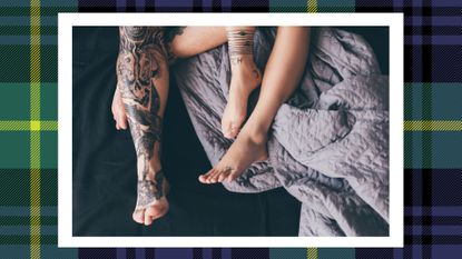 a shot of a couple's feet in bed with tattoos on a blue and green plaid background