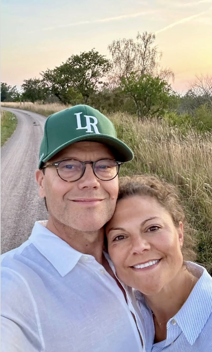 Crown Princess Victoria and Prince Daniel taking a selfie in front of a dirt road with a sunset behind them