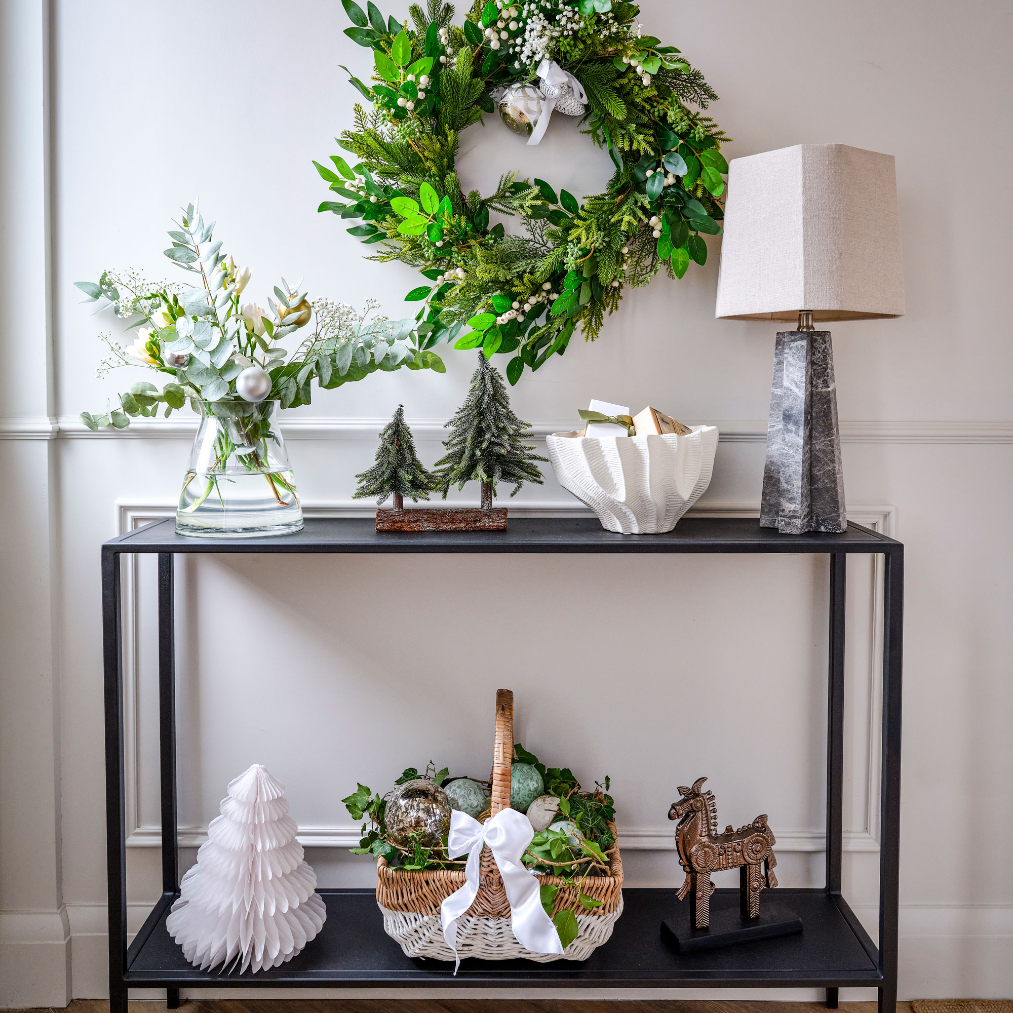 White hallway with black console table with christmas decorations