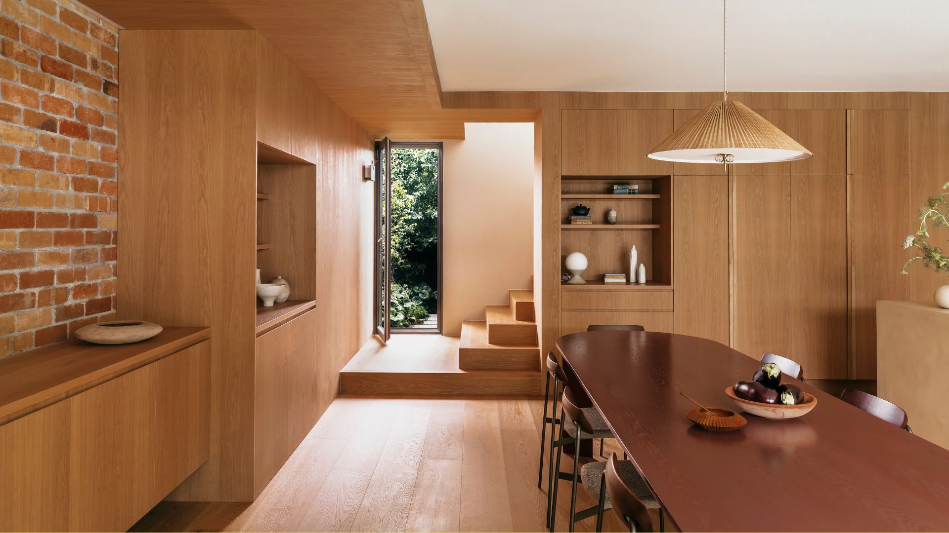 A neutral open concept dining and kitchen space with wood drenched interiors