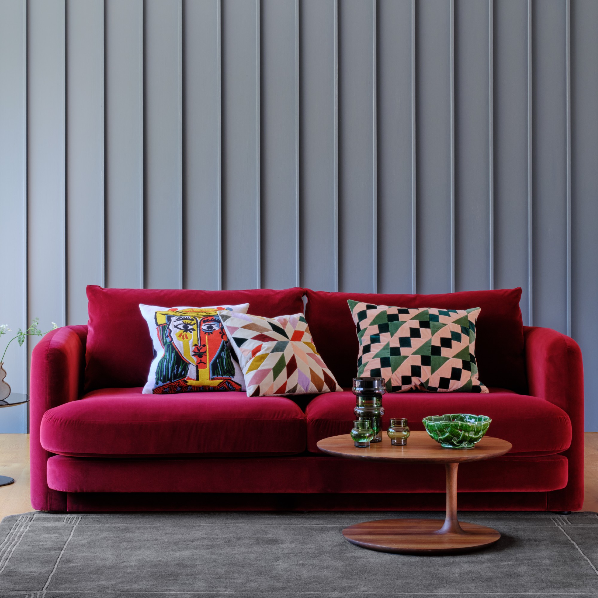 A magenta velvet sofa with colourful patterned cushions