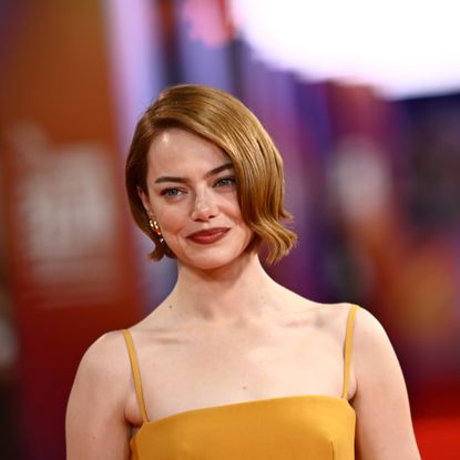 a white woman with short, red hair being photographed at a red carpet film premiere