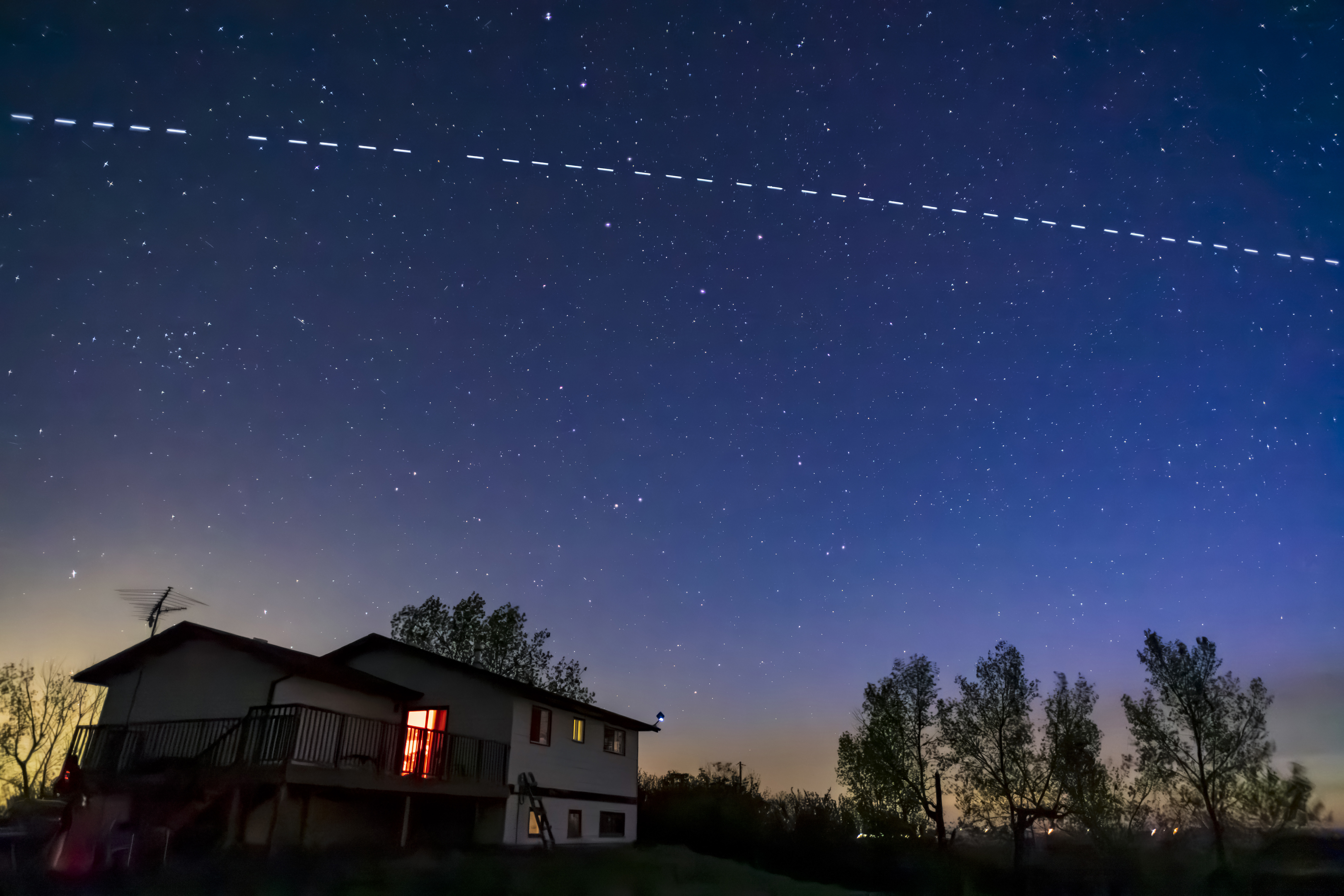 a house with satellite track above in the night sky