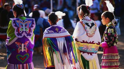 Chumash girls participate in a powwow wearing traditional garments.