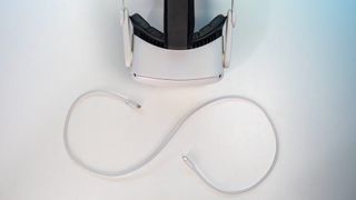 The Meta Quest 2 headset sitting next to a charging cable arranged like an infinity symbol.