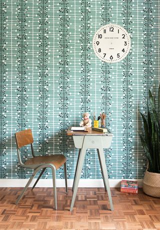 teen/kids bedroom idea with Miss Print wallpaper, old school desk and chair, parquet flooring, plant in basket, clock, stationery
