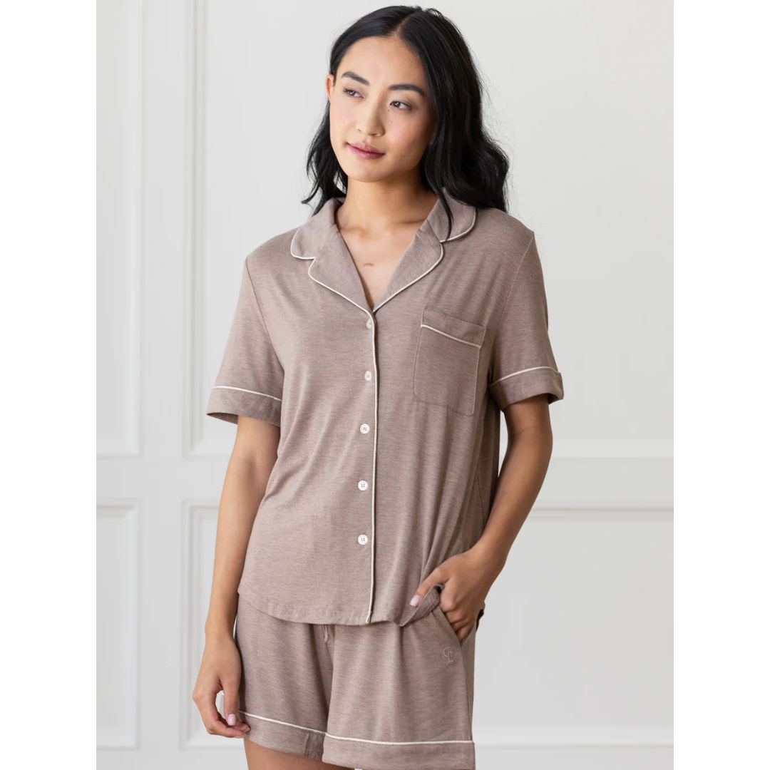 a brunette woman wearing a brown short-sleeved pajama top and short pajama bottoms from cozy earth