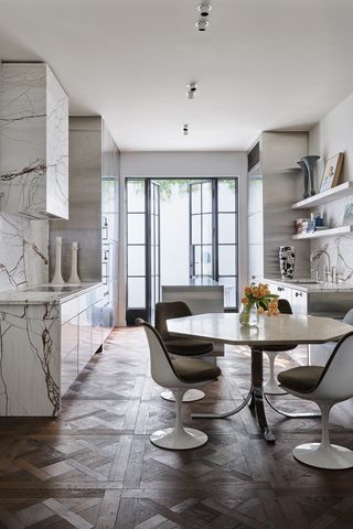 An all marble kitchen with a midcentury dining table