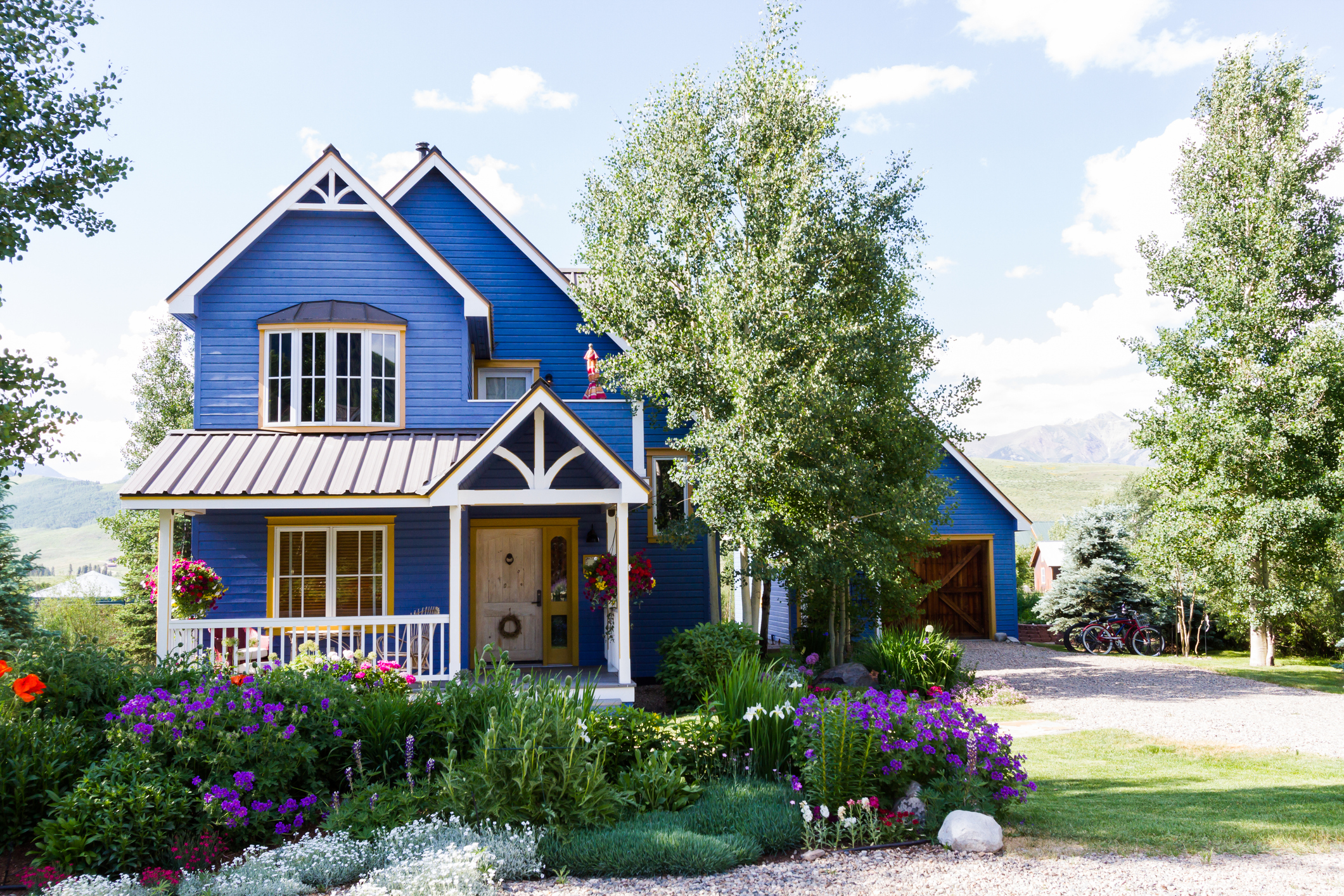 A bright blue mountain home in Crested Butte, Colorado. The home has beautful landscaping and backs up to a mountain view.