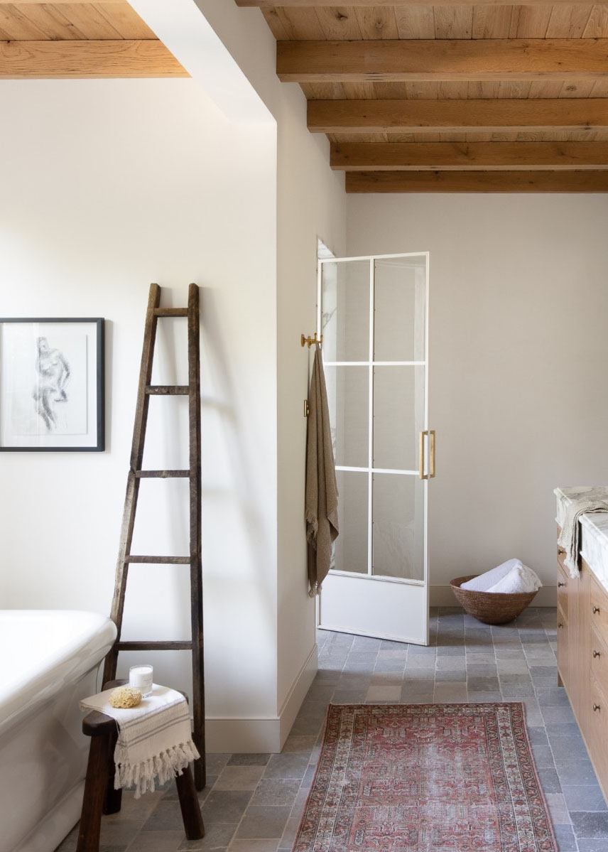 Farmhouse bathroom with wooden-beamed ceiling, grey tiled floor, and ladder feature