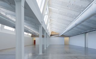 Inside the building. A white interior with a large open space supported by steel beams.