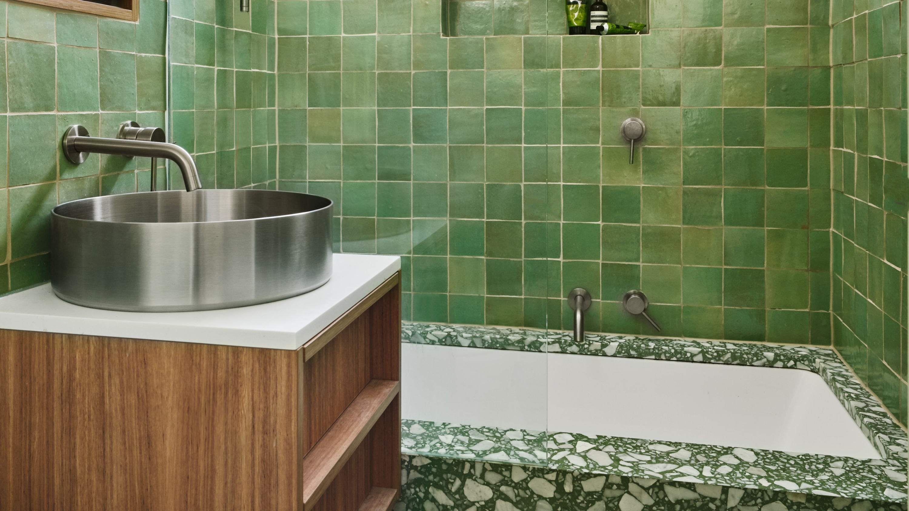green zellige tiles in a bathroom with terrazzo and a chrome sink