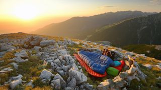 Camper in a bivy sack on a mountain at sunrise
