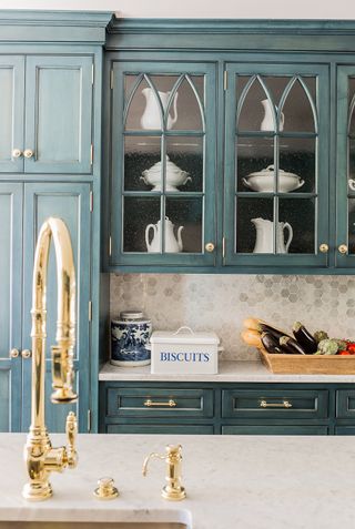 kitchen with distressed teal cabinetry and brass tap and sink K. Marshall Design