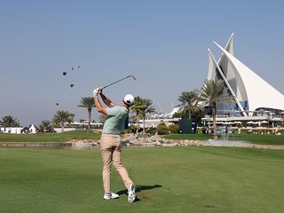 Rory McIlroy hitting an approach shot over water to the 18th green at the Dubai Invitational