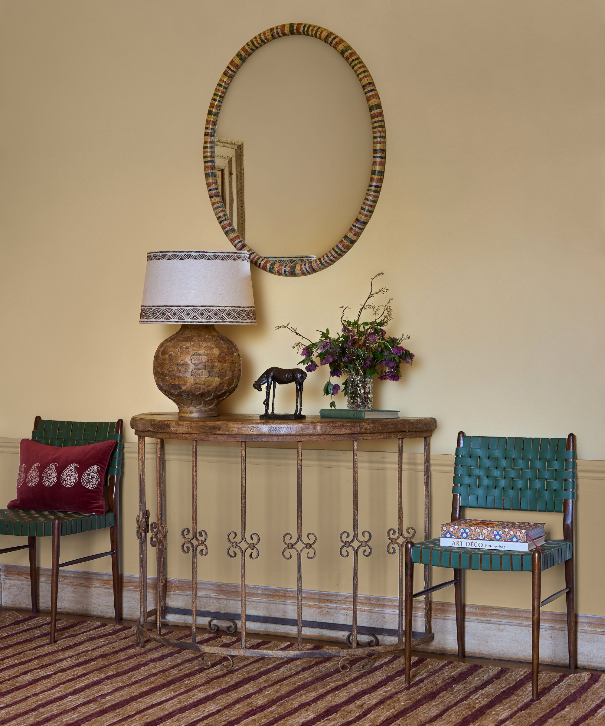 A butter yellow hallway with a striped carpet and an antique demi-lune table
