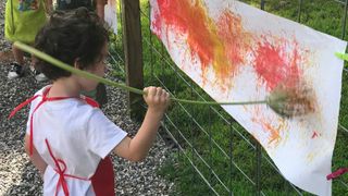 A child uses a plant to paint
