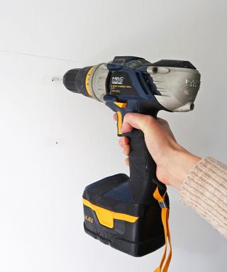 drilling a hole in a wall for putting up a shelf