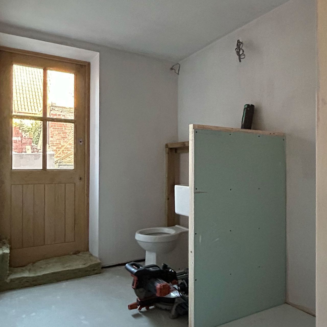 Bathroom mid-renovation with half-height stud wall in middle of room