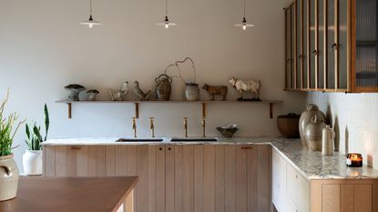Paneled kitchen cabinets in natural wood with marble counters