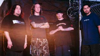 Fear Factory posing for a photograph next to a chain-link fence