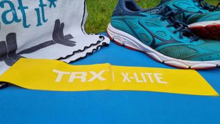 Image shows a TRX Strength Band on a blue yoga mat next to a running shoe.