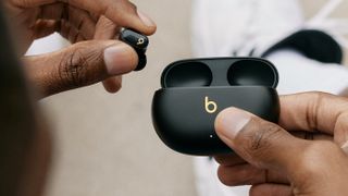 PR lifestyle image of Beats Studio Buds Plus in black/gold being removed from charging case