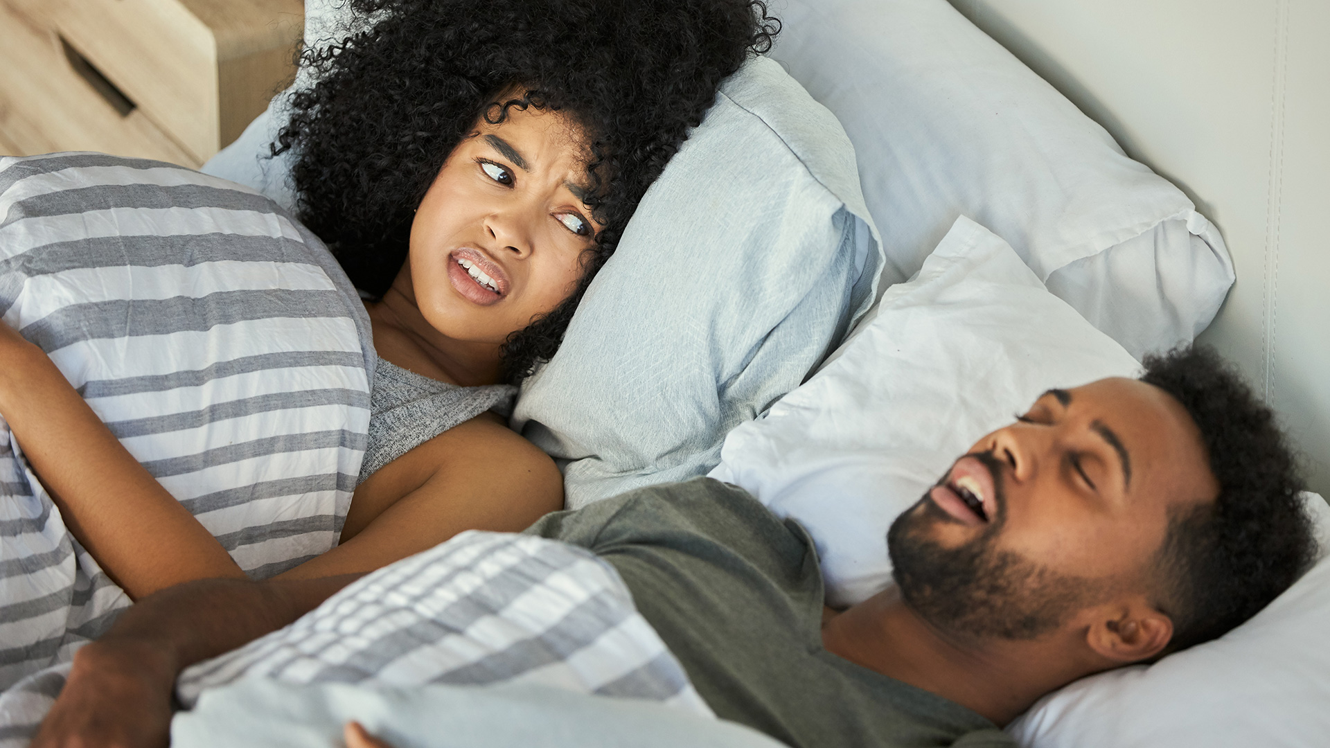 Woman in bed, woken up by her snoring partner