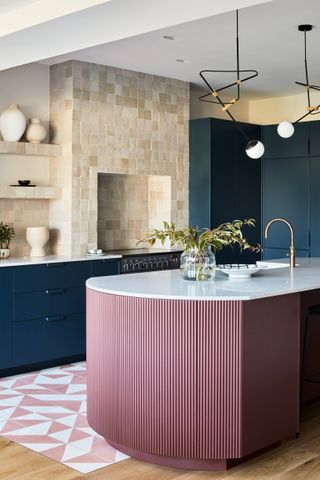A kitchen with pink island and white counter