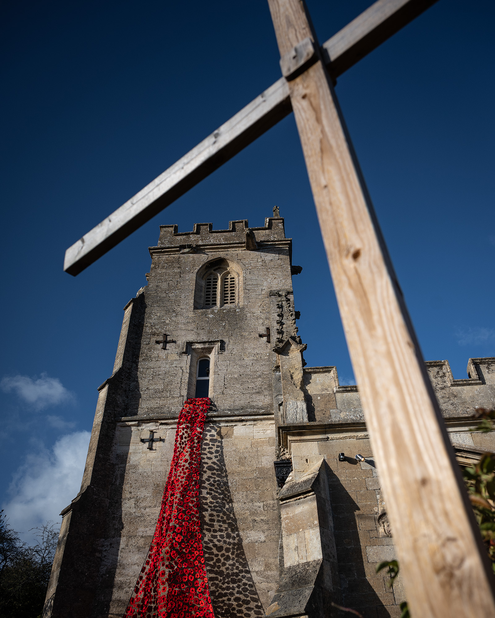 Image of church with cross in foreground and red poppies spilling from window