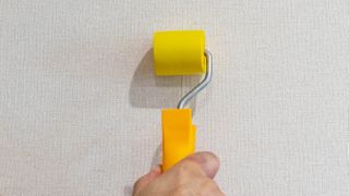 Using a seal roller along wallpaper seal