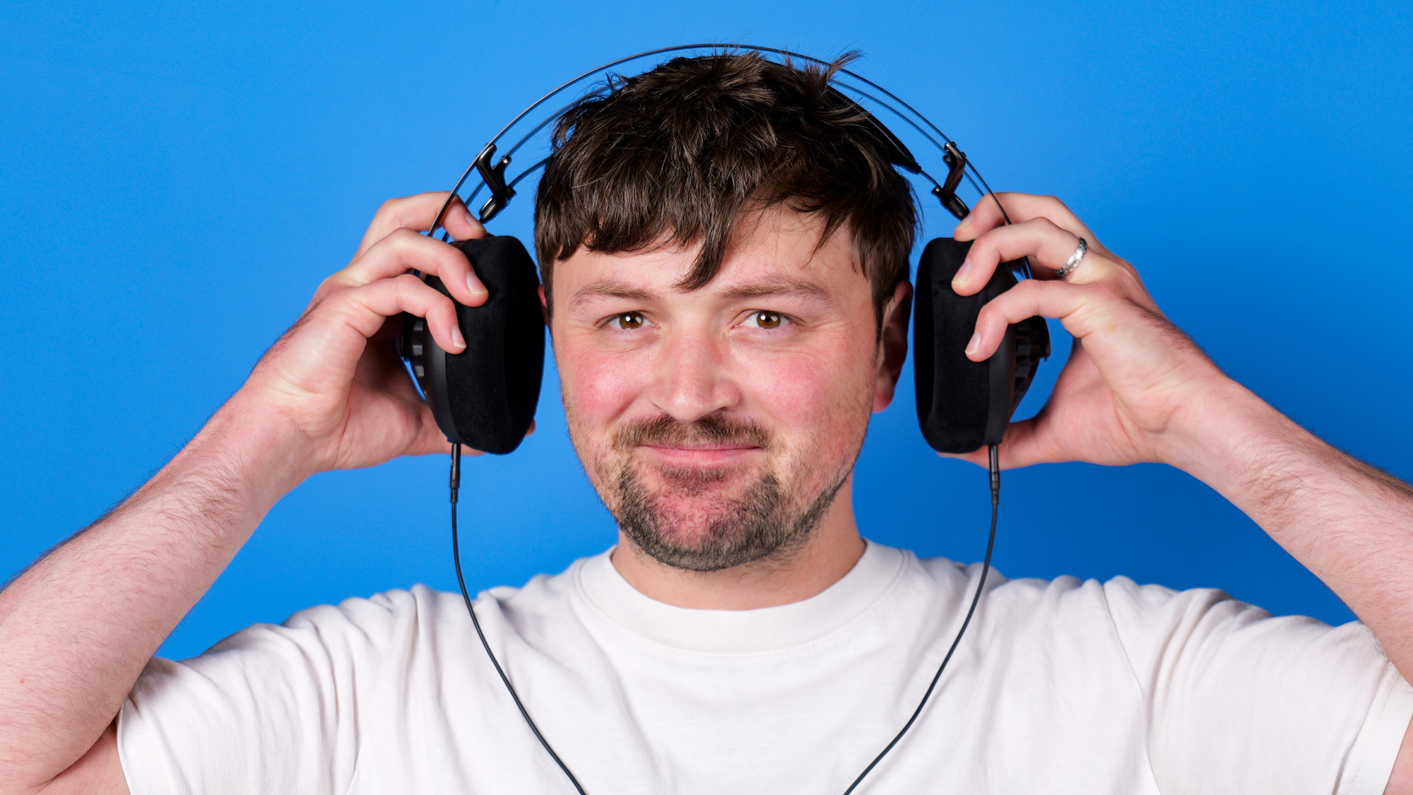 A man putting on the Meze 105 AER pulling out the earcups to fir the headband on his head