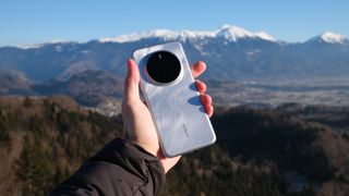 Honor Magic7 Pro phone held in a hand in front of a mountainous backdrop